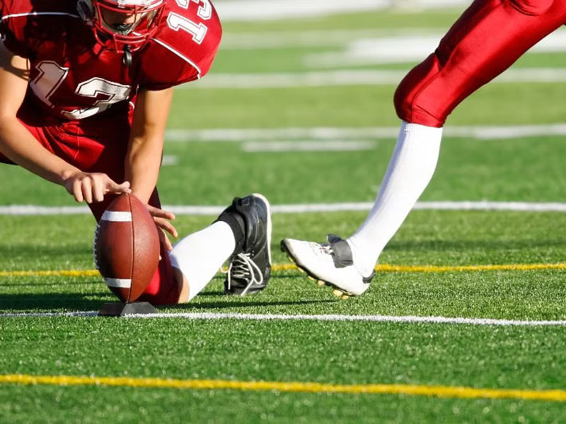 A football player kneels on the field